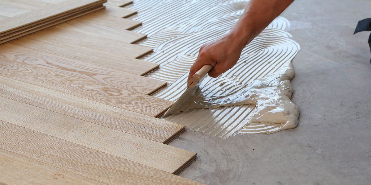 Installer setting wide-plank oak flooring into adhesive