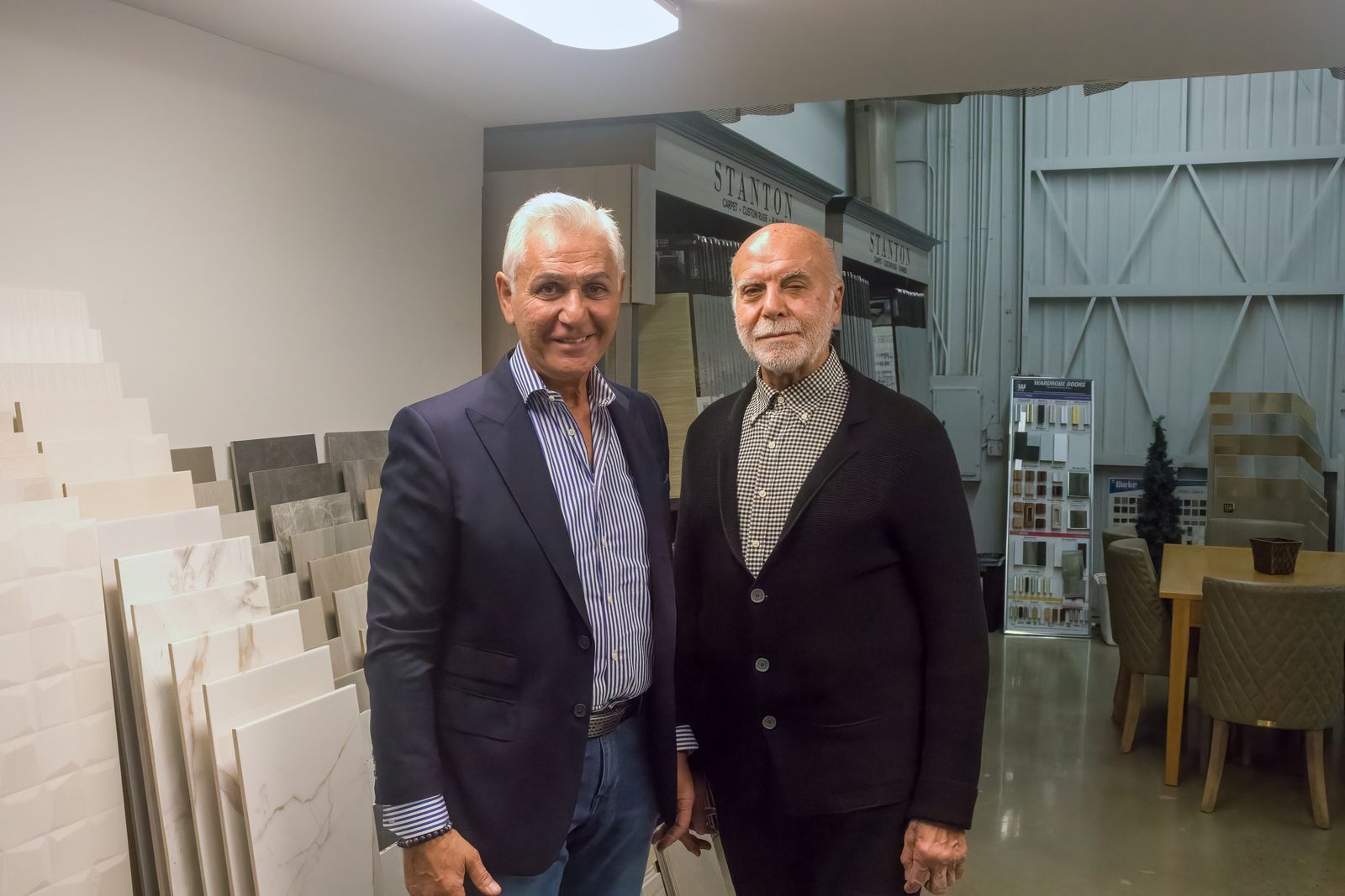 Brothers Bruce and Amir Ghavami standing among tile samples
